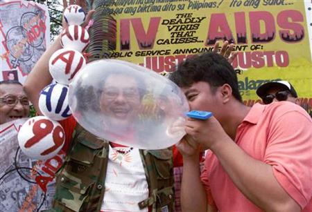 A Filipino AIDS awareness advocate blows up a condom during a street campaign to encourage safe sex on World AIDS Day in Manila